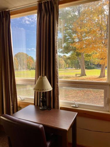 A desk table in a guest room that is positioned towards a window and overlooks a leaf covered lawn. 
